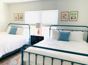 A bedroom with two beds, a nightstand, and a window with blinds. - 3-bedroom townhome STEPS to the beach in gorgeous New Smyrna Beach, pet-friendly (New Smyrna Beach)