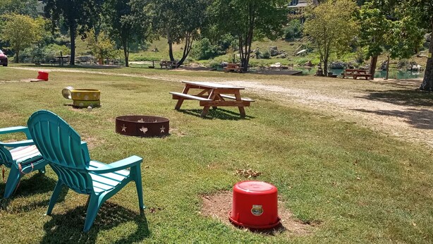 Een picknickplaats met een tafel, stoelen, een brandblusser en een kleine vijver.