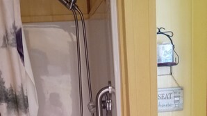 Een douche met glazen deur, een toilet en een douchegordijn met een hertenprint.