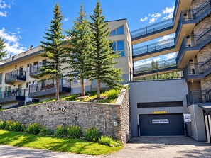 A multi-story residential building with a stone facade, a garage entrance, and a sign indicating a clear height of 6 feet 10 inches. - True Ski-In/Ski-Out, Mountain Views with Garage & Elevator (Mt Crested Butte)
