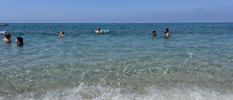 A beach with clear water and pebbles.