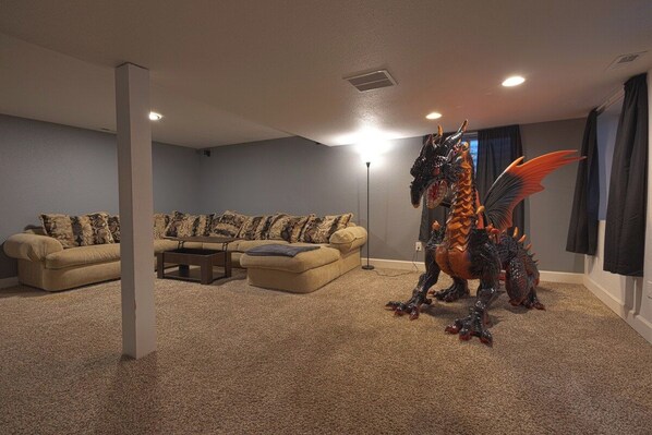 Un salon avec un tapis beige, un canapé agrémenté de coussins à motifs et une statue de dragon décorative.