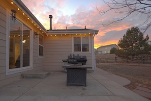 A house with a barbecue grill and string lights on the porch. - Spacious 4BR Home - Sleeps 8 - Home Theater, Fenced Yard & BBQ (Thornton)