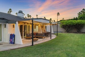 A house with a covered patio, outdoor seating, and a well-maintained lawn. - The Marilyn: Gorgeous 4-bedroom House with AC in Sunny Palm Springs (Palm Springs)