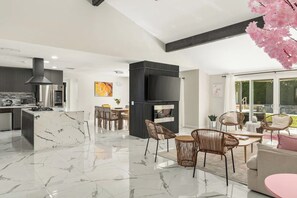 A modern kitchen with a marble island, a built-in stove, and a large black range hood. - The Marilyn: Gorgeous 4-bedroom House with AC in Sunny Palm Springs (Palm Springs)