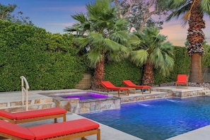 A swimming pool with red lounge chairs, a stone deck, and a palm tree. - The Marilyn: Gorgeous 4-bedroom House with AC in Sunny Palm Springs (Palm Springs)
