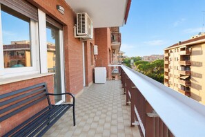A balcony with a bench, air conditioning unit, and a view of neighboring buildings. - Elegantis Trastevere Family Apartment with Terrace (Roma)