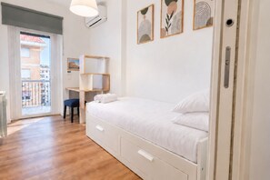 A bedroom with a bed, a desk, a chair, and a view of the outside. - Elegantis Trastevere Family Apartment with Terrace (Roma)