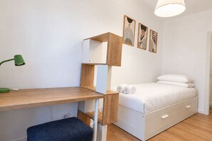 A bedroom with a bed, a desk, a chair, and a bedside table. - Elegantis Trastevere Family Apartment with Terrace (Roma)