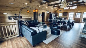 A cabin interior with a living area, dining space, and a kitchen. - 8BR • 25 Beds • Indoor Pool • Tiki Bar • Hot Tub (Sevierville)