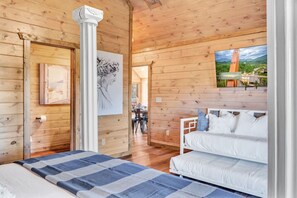 Ein Holzhütten-Interieur mit Bett, Essbereich und Blick auf eine Berglandschaft.