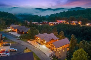 Ein Resort mit mehreren Ferienhäusern, einem Parkplatz und Blick auf die umliegenden bewaldeten Hügel.