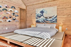 A traditional Japanese-style room with a tatami mat bed, a wooden door, and a wall adorned with fans and a large wave painting. - 8BR • 25 Beds • Indoor Pool • Tiki Bar • Hot Tub (Sevierville)