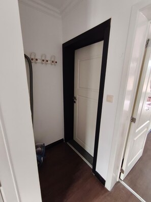 A hallway with a white door, a black trim, and a white wall with a light switch. - Lovely 1-bedroom apartment in cool Leuven perfect for your stay (Leuven)