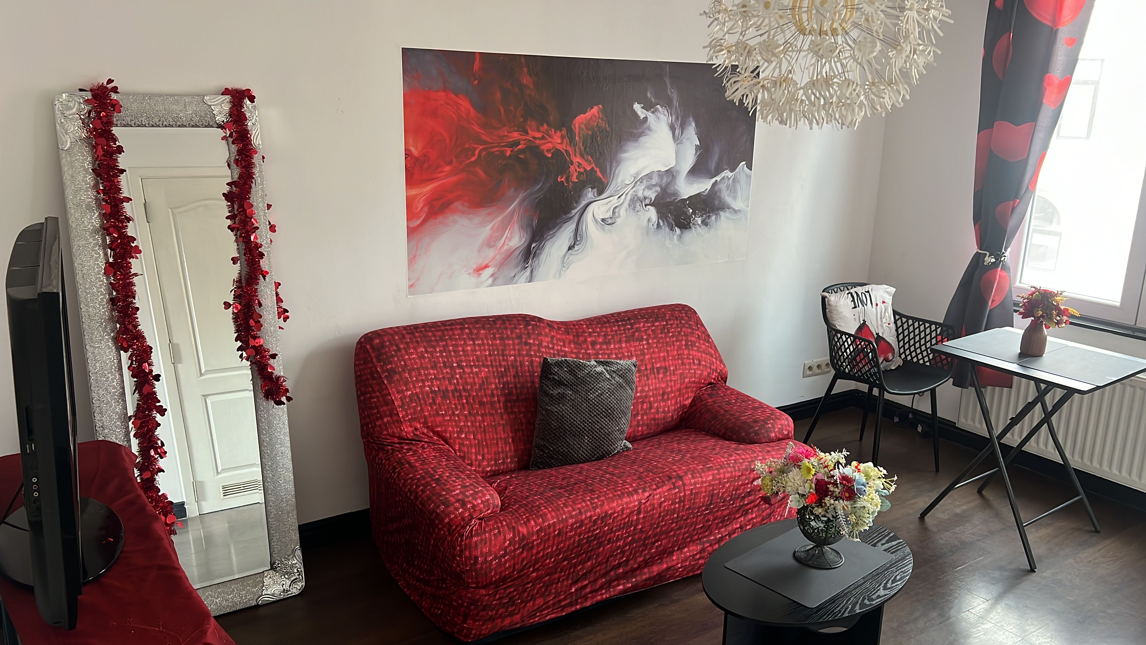 A living room with a red sofa, a large abstract painting, and a decorative mirror.