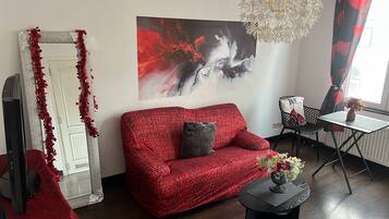 A living room with a red sofa, a large abstract painting, and a decorative mirror.