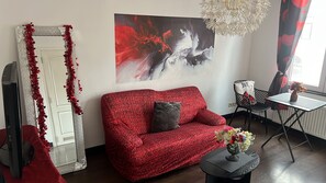 A living room with a red sofa, a large abstract painting, and a decorative mirror. - Lovely 1-bedroom apartment in cool Leuven perfect for your stay (Leuven)