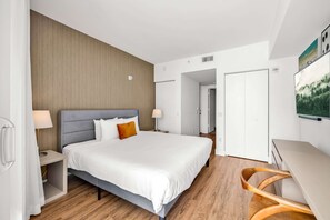 Ein modernes Hotelzimmer mit einem großen Bett, Holzboden, einem Schreibtisch und einem Stuhl.