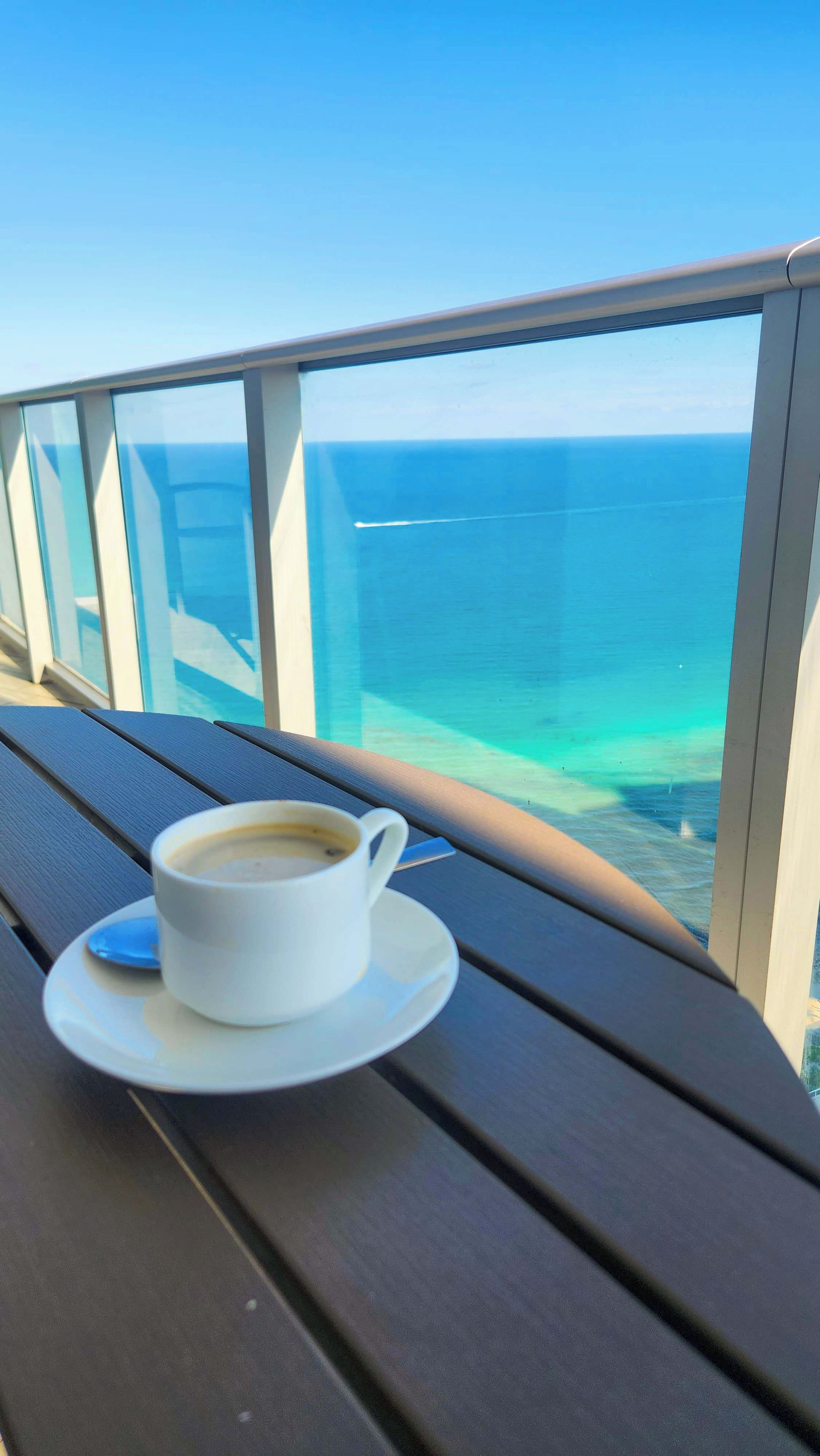 Een witte koffiekop op een tafel met uitzicht op zee.