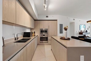 A modern kitchen with wooden cabinets, stainless steel appliances, and a central island. - 23rd Floor Double Condo Ocean Views and Pools (Hollywood)