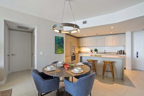 A modern kitchen with a central island, a dining area with round table and chairs, and a pendant light fixture. - 23rd Floor Double Condo Ocean Views and Pools (Hollywood)