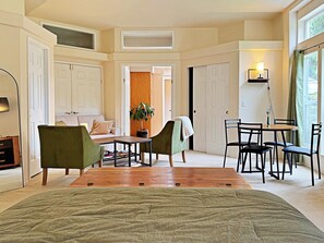 A room with a bed, a sofa, a table, chairs, and a lamp. - Lavender Suite on the Dungeness River (Sequim)