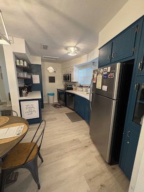 Eine moderne Küche mit einem Edelstahl-Kühlschrank, blauen Schränken und einem Essbereich mit Tisch und Stühlen.