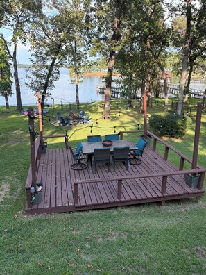 Eine Holzterrasse mit Tisch und Stühlen mit Blick auf einen See.