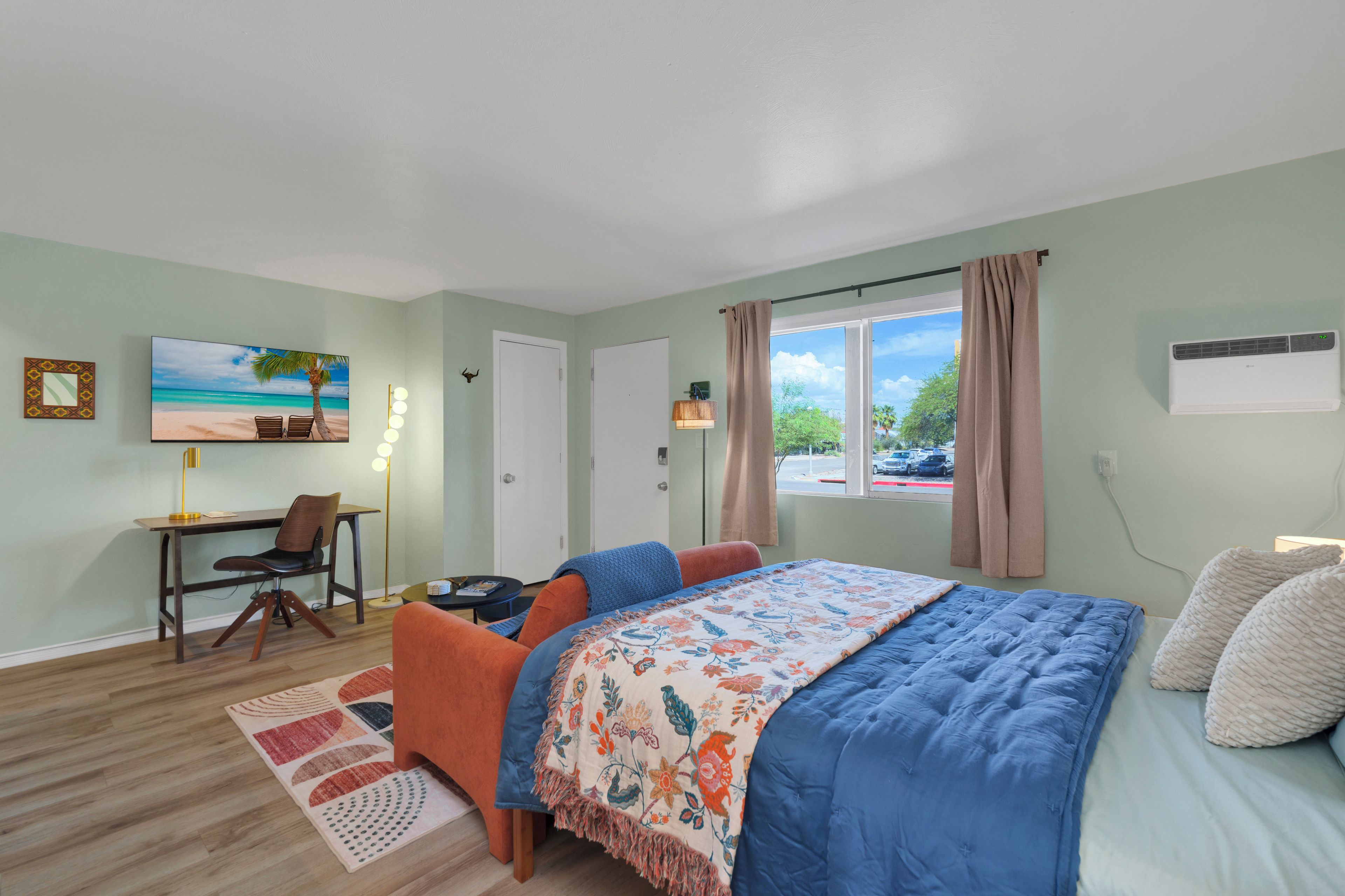 A room with a bed, a desk, a chair, a lamp, and a window with curtains.