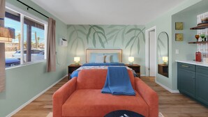 Une chambre à coucher comprenant un lit, une table de chevet, une chaise, une fenêtre avec des rideaux et un mur orné d’un motif de feuilles.