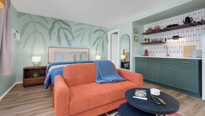 Un salon moderne avec un canapé, une petite table basse et un coin cuisine doté d’étagères.