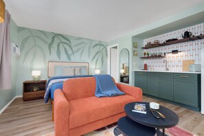 Ein modernes Wohnzimmer mit einer Couch, einem kleinen Couchtisch und einer Küchenzeile mit Regalen.