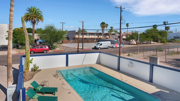 Une piscine avec des chaises longues, un panneau de signalisation indiquant un arrêt obligatoire et un bâtiment en arrière-plan.