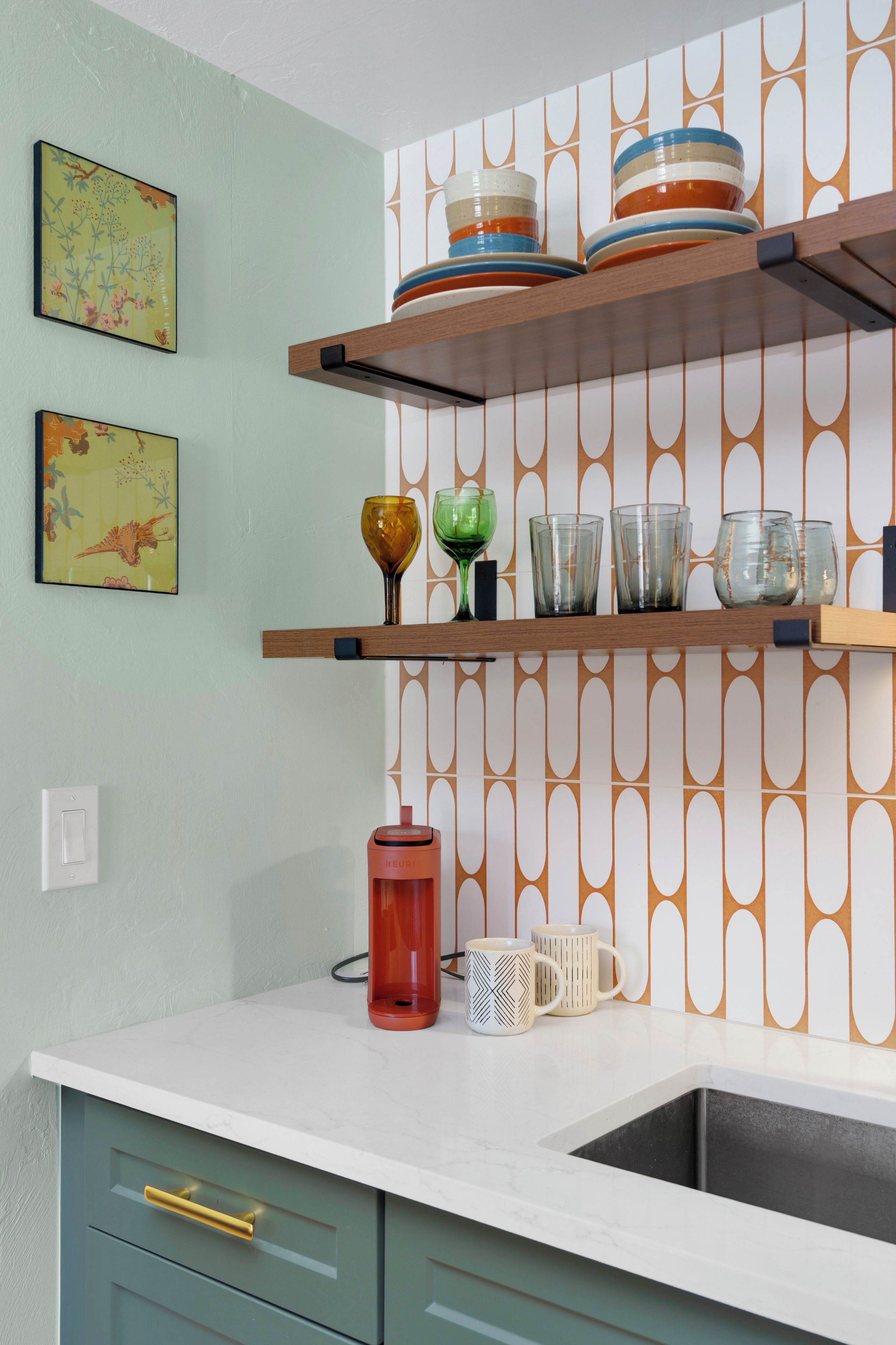 A kitchen with a white countertop, two wooden shelves, and a patterned backsplash.