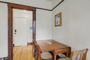 A dining area with a wooden table and chairs, a door leading to another room, and a framed picture on the wall. - Historic Bozeman Flat, Gas Fireplace, Walk Main (Bozeman)