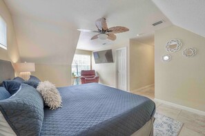A bedroom with a large bed, a ceiling fan, a chair, and a door. - Riverfront Retreat | Sleeps 14 | Pool | Spa | Deck (Tampa)
