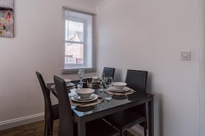A dining table set with plates, glasses, and cutlery, with chairs around it. - Oriel House • Sleeps 6 • Free Parking • Work Desk • Fast WIFI • Self-Check-In • By Yoko Property (Milton Keynes)