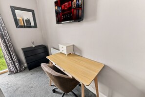 A room with a desk, chair, black dresser, white nightstand, and a wall-mounted TV displaying Netflix. - Luxury Flat • City Centre • Balcony • FreeParking • Fast WiFi • Work Desk • SmartTVs • Yoko Property (Milton Keynes)