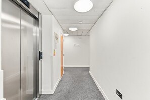 A hallway with a door on the left, a light fixture on the ceiling, and a sign on the wall. - Luxury Flat • City Centre • Balcony • FreeParking • Fast WiFi • Work Desk • SmartTVs • Yoko Property (Milton Keynes)