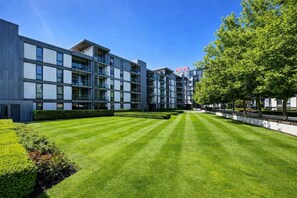 A modern apartment building with multiple balconies, a well-maintained lawn, and a clear sky. - Luxury Flat • City Centre • Balcony • FreeParking • Fast WiFi • Work Desk • SmartTVs • Yoko Property (Milton Keynes)