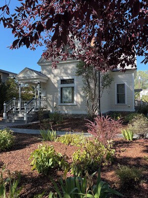A two-story house with a covered porch and a front yard with various plants. - Cozy 3-bedroom house in fabulous Bozeman with AC (Bozeman)