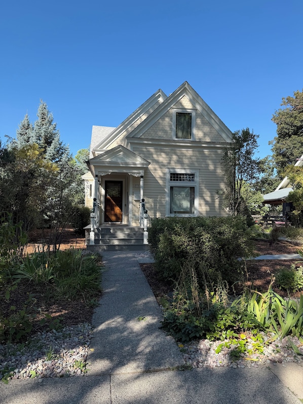A two-story house with a front porch, a visible door, and a small window with a QR code. - Cozy 3-bedroom house in fabulous Bozeman with AC (Bozeman)