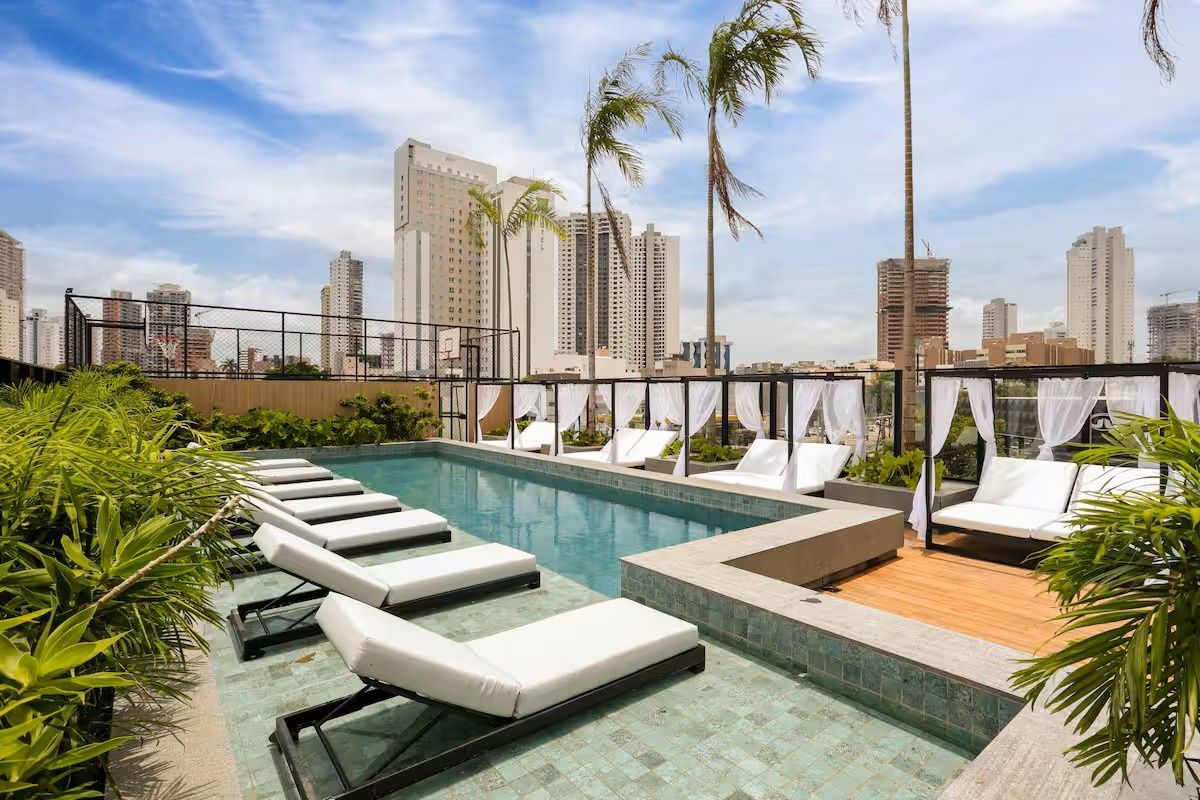A rooftop pool area with lounge chairs and a view of the city skyline.