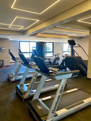 A gym with multiple treadmills, exercise bikes, and a stair climber. - Premium Apartment in Setor Bueno | Full-Service Condominium with Heated Pools (Goiânia)