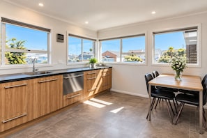 Une cuisine moderne avec des meubles en bois, des appareils électroménagers en acier inoxydable et un coin repas comprenant une table et des chaises.