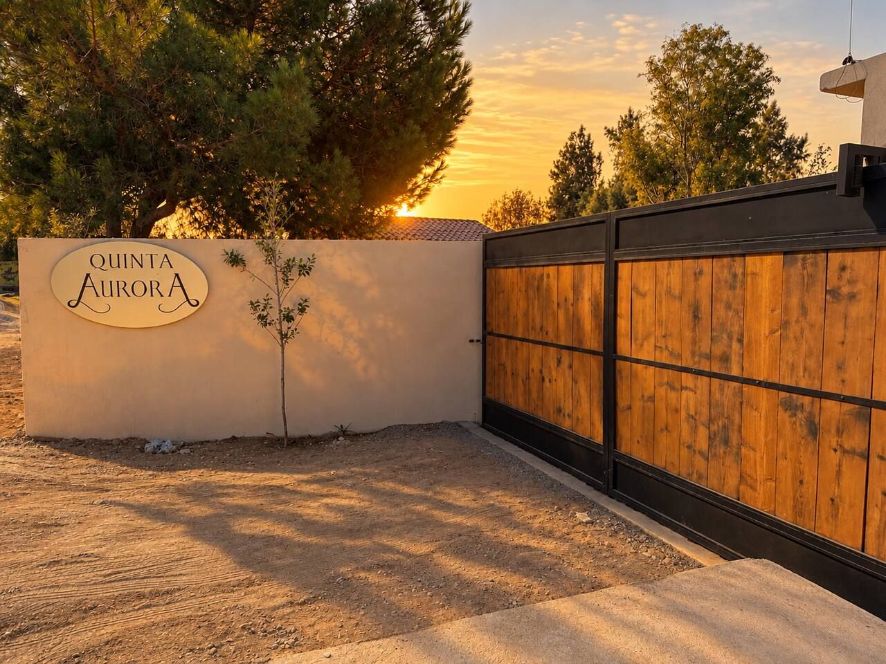 Una entrada con puerta y un letrero que dice 'QUINTA AURORA', con un pequeño árbol a un lado.