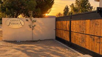 Una entrada con puerta y un letrero que dice 'QUINTA AURORA', con un pequeño árbol a un lado.