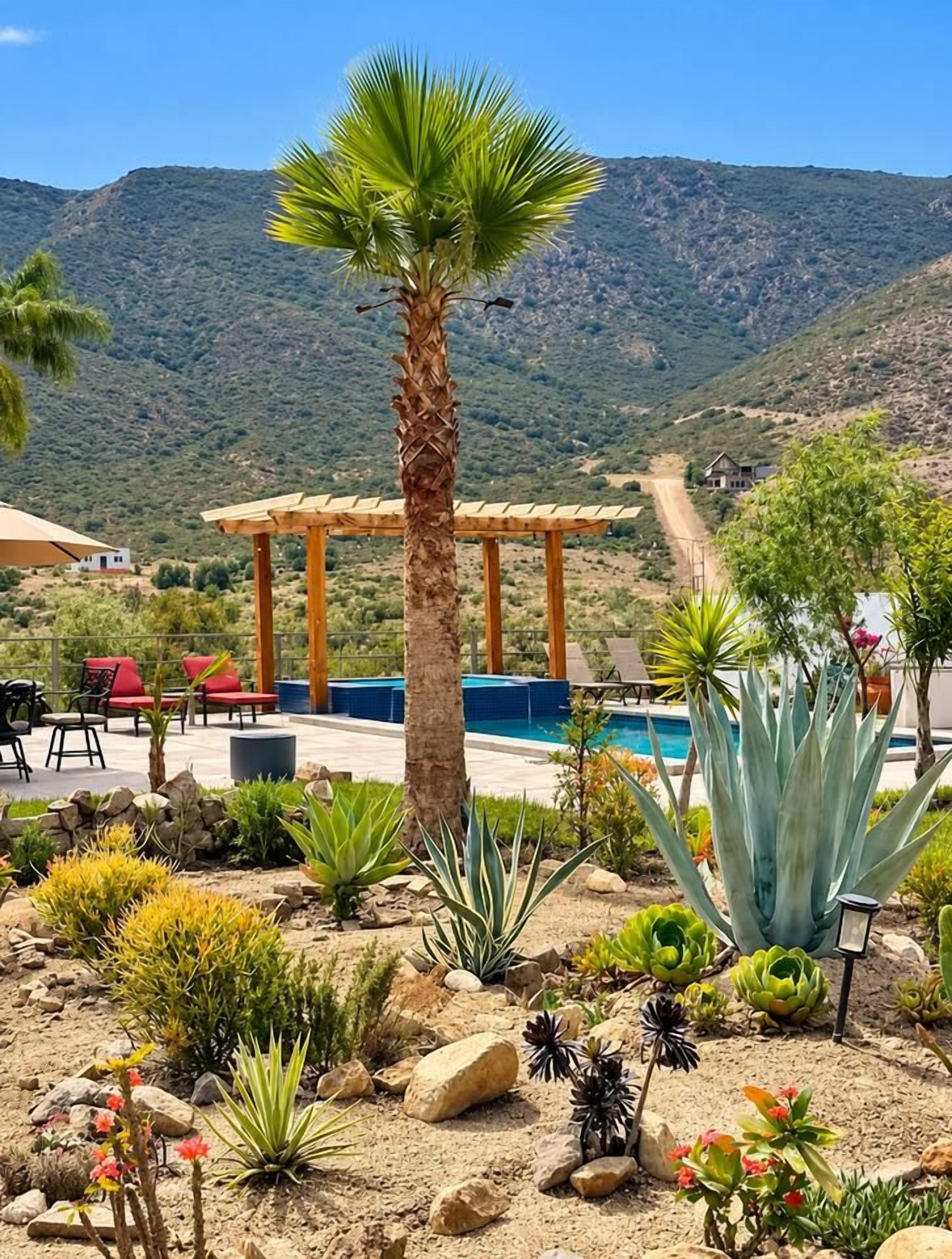 A patio with outdoor furniture, a pool, and a mountain backdrop.