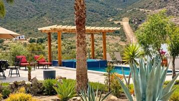 A patio with outdoor furniture, a pool, and a mountain backdrop.