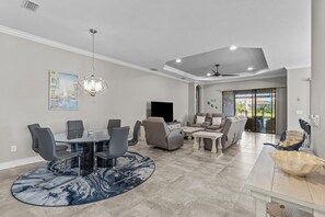 A spacious living area with a dining table, chairs, a sofa, and a television. - 3BR/3BA · Private Heated Pool · Gated Resort · Near Venice & Gulf Beaches (Nokomis)